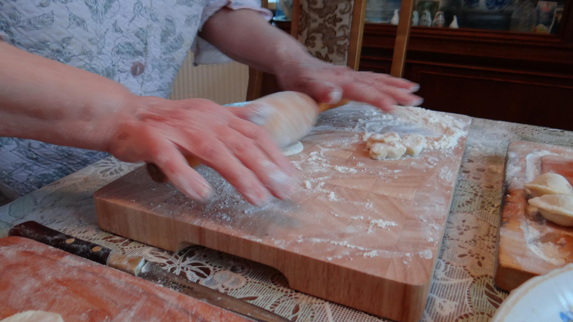 Close-up of hands preparing dough on wooden board
