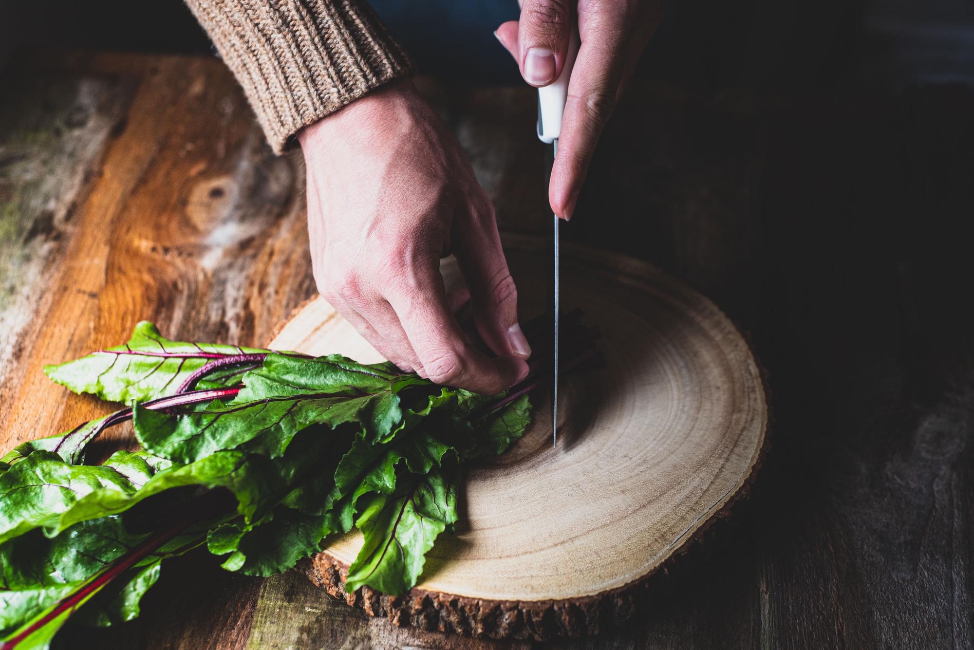 Hands slicing herbs with mandoline